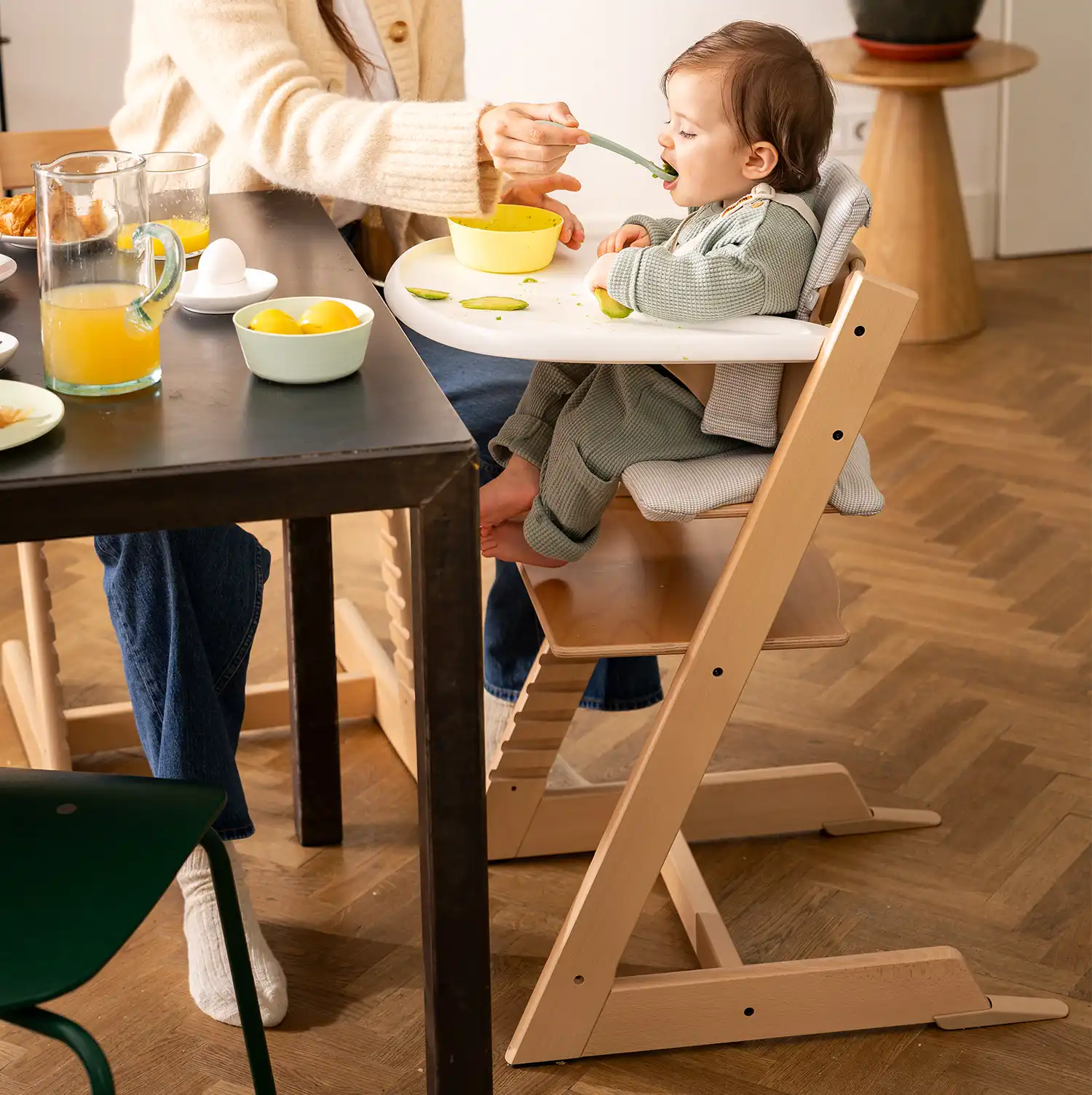 Dziewczynka prawidłowo siedząca w ergonomicznym krzesełku Stokke Tripp Trapp z Baby Set oraz tacką kolorze naturalny buk