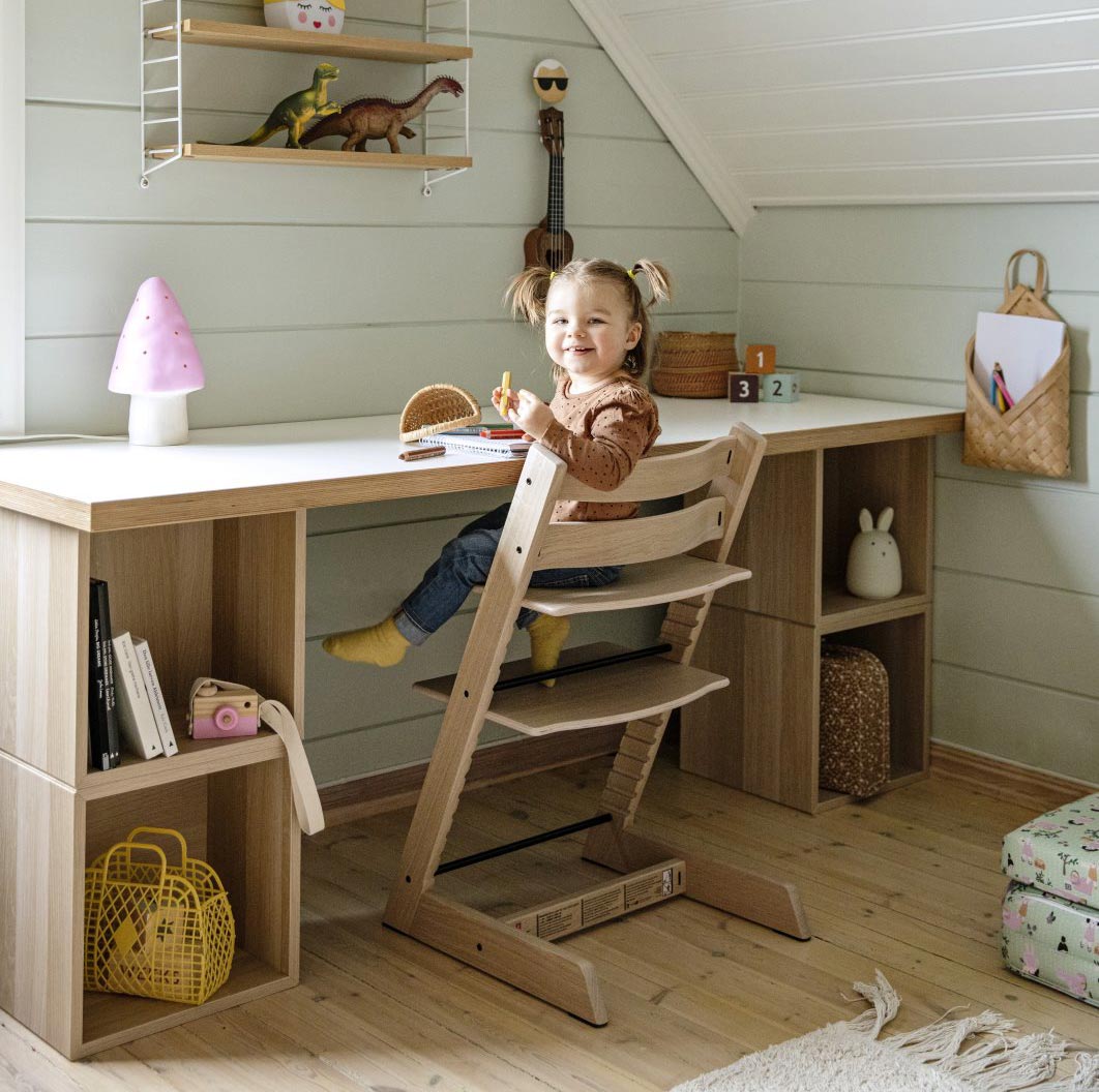 dziewczynka siedząca przy biurku na krzesełku Stokke Tripp Trapp Oak Natural